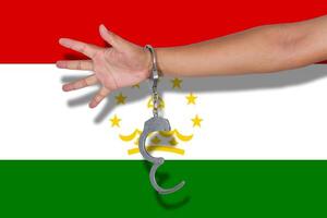 handschellen mit hand auf tadschikistan-flagge foto