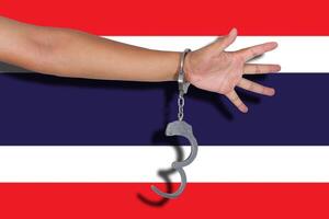 Handschellen mit der Hand auf der thailändischen Flagge foto