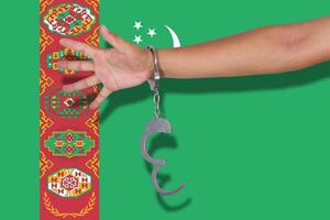 handschellen mit der hand auf der turkmenischen flagge foto