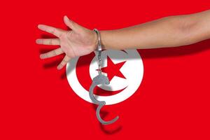 handschellen mit der hand auf der tunesischen flagge foto