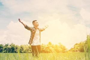 Freiheit junger Teenager, der seine Arme in den Himmel streckt, genießt und freut sich über die frische Luft auf der Wiese.