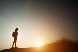 Silhouette einer Frau, die mit Sonnenuntergang wandert. foto