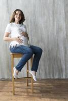 schwangeres Mädchen auf grauem Hintergrund. foto