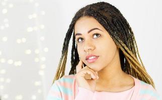 Portrait kokette schwarze Frau mit Dreadlocks auf verschwommenem Hintergrund eines Spiegels mit Bokeh foto