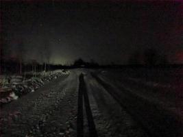 verschneite Straße in einer mondhellen Winternacht im Dorf foto