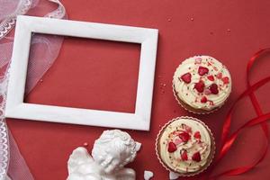 flache komposition für valentinstaggrüße. Cupcakes, Engel, Rahmen auf rotem Hintergrund. Kopieren Sie Platz für Ihren Text foto