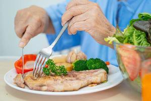 asiatische senior oder ältere alte damenpatientin, die frühstück und gemüse gesundes essen mit hoffnung und glücklich isst, während sie im krankenhaus sitzt und hungrig auf dem bett sitzt. foto