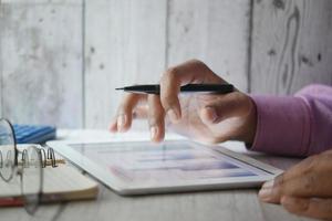 Die Hand des Mannes arbeitet an einem digitalen Tablet am Schreibtisch, mit selbst erstelltem Diagramm foto