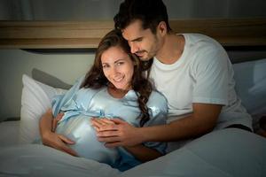 schwangere frau mit ehemann im schlafzimmer mit der atmosphäre, spaß beim reden zu haben foto