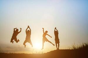 Kinder, die auf der glücklichen Zeit des Sommersonnenuntergangs spielen foto