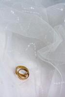 zwei Eheringe, die auf Hochzeitskleid legen foto