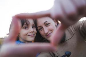 Junge mit Mama gefalteten Fingern in Form eines Herzens. foto