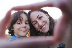 Junge mit Mama gefalteten Fingern in Form eines Herzens. foto