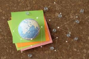 handgezeichneter texturglobus und soziales netzwerkdiagramm mit pin und haftnotiz auf korktafel als konzept foto