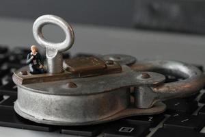 internet-sicherheitskonzept-miniaturgeschäftsmann stehen auf altem schlüssel und vorhängeschloss auf laptop-computertastatur foto