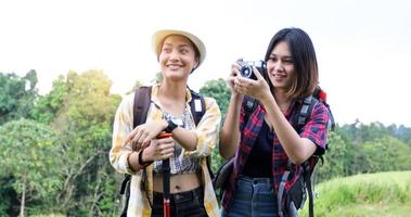 Asiatische Gruppe junger Leute, die mit Freunden wandern, Rucksäcke, die zusammen spazieren gehen und eine Karte suchen und eine Fotokamera an der Straße machen und glücklich aussehen, entspannen Sie sich bei Urlaubskonzeptreisen foto