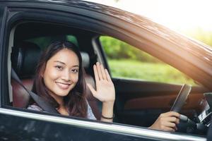 schöne asiatische Frau, die lächelt und genießt. Autofahren auf der Straße für Reisen foto