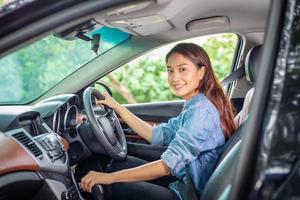 schöne asiatische Frau, die lächelt und genießt. Autofahren auf der Straße für Reisen foto