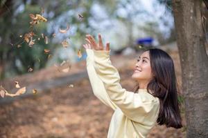 schöne asiatische Frau, die glückliches Mädchen lächelt und warme Kleidung trägt Winter- und Herbstporträt im Freien im Park foto