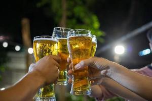 asiatische gruppe von freunden, die eine party mit alkoholischen biergetränken feiern, und junge leute, die an einer bar cocktails anstoßen und mit gläsern klirren foto