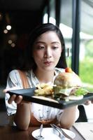 asiatische Frauen lächelten und glücklich und genossen es, Hamburger im Kaffee und Restaurant in der Entspannungszeit zu essen? foto