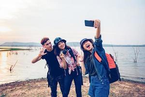 asiatische gruppe junger leute mit freunden und rucksäcken, die zusammen spazieren gehen, und glückliche freunde machen foto und selfie, entspannen zeit auf urlaubskonzeptreisen