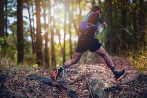 ein Mann Läufer der Spur. und die Füße des Athleten, die Sportschuhe für Trailrunning im Wald tragen foto