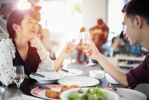 asiatische junge paare genießen ein romantisches abendessen mit getränken, während sie zusammen am esstisch in der küche sitzen foto