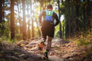 ein Mann Läufer der Spur. und die Füße des Athleten, die Sportschuhe für Trailrunning im Wald tragen foto