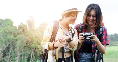 Asiatische Gruppe junger Leute, die mit Freunden wandern, Rucksäcke, die zusammen spazieren gehen und eine Karte suchen und eine Fotokamera an der Straße machen und glücklich aussehen, entspannen Sie sich bei Urlaubskonzeptreisen foto