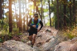 ein Mann Läufer der Spur. und die Füße des Athleten, die Sportschuhe für Trailrunning im Wald tragen foto