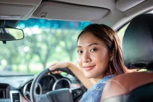 schöne asiatische Frau, die lächelt und genießt. Autofahren auf der Straße für Reisen foto