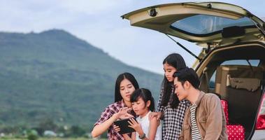 glückliches kleines Mädchen mit asiatischer Familie, die im Auto sitzt, um Roadtrip und Sommerurlaub im Wohnmobil zu genießen? foto