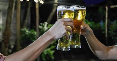 asiatische gruppe von freunden, die eine party mit alkoholischen biergetränken feiern, und junge leute, die an einer bar cocktails anstoßen und mit gläsern klirren foto
