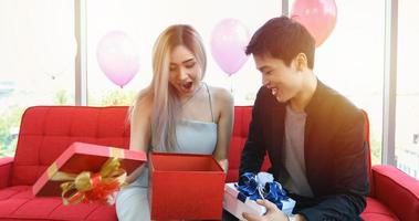 asiatische paarliebhaber geben eine geschenkbox mit weihnachtsgeschenk in den weihnachtsferien und einem guten rutsch ins neue jahr pastetchen foto