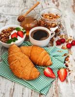 Croissant, Kaffee, Müsli und Erdbeere foto