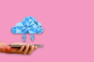 cloud-datenspeicherkonzept. Smartphone oder Handy in der Hand mit Polygon-Cloud-Computing-Übertragungsdaten auf rosa Hintergrund. Kommunikation von Geschäft und Finanzen. foto