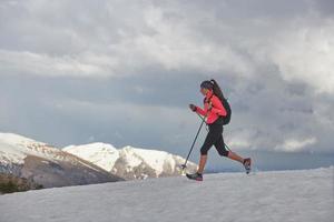 Sportlerin läuft auf dem Schnee zum Skyrunning-Training foto