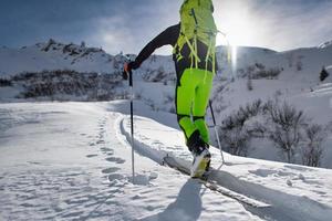 Kletterer mit Bergskifahren geht einen ausgetretenen Pfad hinauf foto