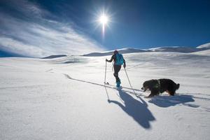 Mädchen macht Skibergsteigen mit seinem Hund an einem märchenhaften Ort foto