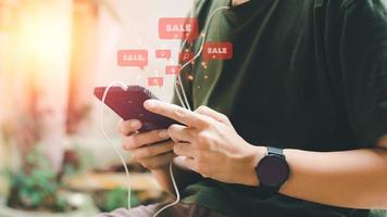 Online-Shopping-Konzept. Hand, die schwarzes Smartphone mit rotem Popup-Verkaufssymbol hält. schwarzer freitag und shoppen zu hause. foto