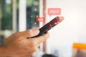 Online-Shopping-Konzept. Hand, die schwarzes Smartphone mit rotem Popup-Verkauf hält. schwarzer freitag und shoppen zu hause. foto