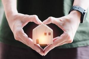 Trautes Heim, Glück allein. Holzhaus in verschwommener Herzform Handhaltung. kleines Haus mit Liebe. foto