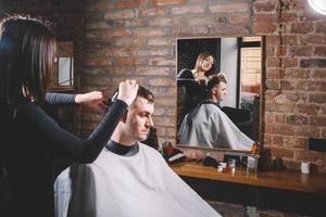 Schöne Friseurin, die die Haare des Kunden mit einer Schere in einem Friseursalon schneidet. konzept von werbung und friseur foto