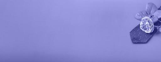 blaue Krawatte mit einer Teerose auf einem sehr peri Hintergrund. Weihnachtsgeschenke Nahaufnahme mit Textfreiraum foto