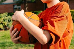 Teenager Junge eingewickelt seine Hände um das Ball nach spielen Basketball foto