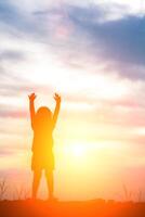 kleine mädchen seine hand, um freude und glück bei sonnenuntergang .silhouette konzept zu zeigen foto