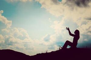 Silhouette einer Frau, die über einem schönen Himmelshintergrund betet foto