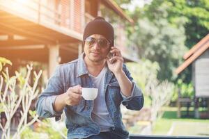 hipster-mann, der sich auf dem heimischen balkon mit der kaffeetasse in der hand ausruht, entspannendes urlaubskonzept. foto