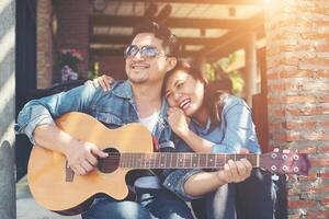 Hipster-Paar sitzt entspannt in netter Atmosphäre beim ersten Date und spielt gerne Gitarre als tolle Zeit zusammen. foto